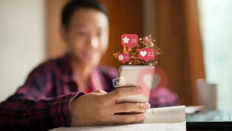 Close-up of a person holding a smartphone with floating social media notification icons for likes, comments, and stars.